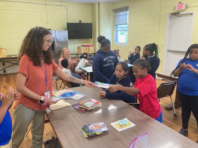 Teacher and students reading books in classroom.