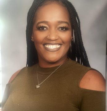 A lady wearing a brown top, smiling at the camera